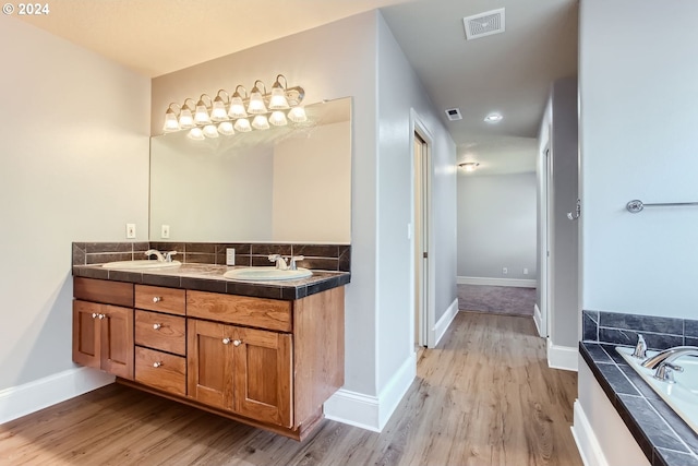 bathroom with a bathing tub, hardwood / wood-style floors, and vanity