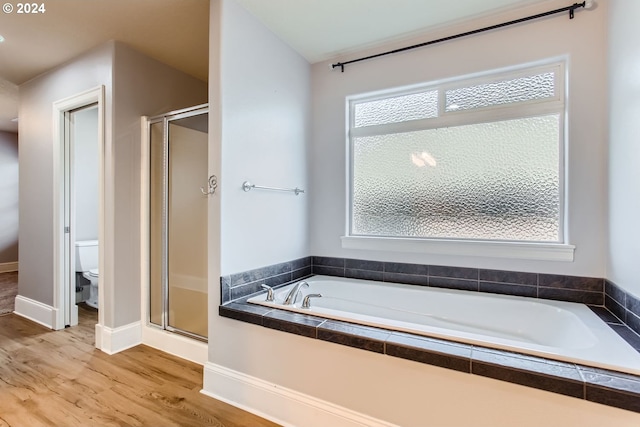 bathroom with hardwood / wood-style flooring, toilet, and shower with separate bathtub