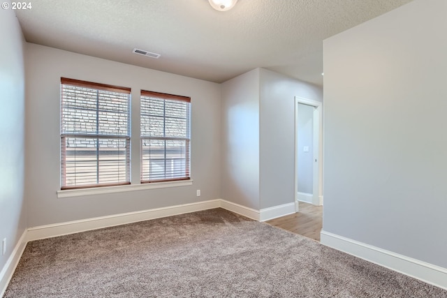 empty room featuring a textured ceiling and light carpet