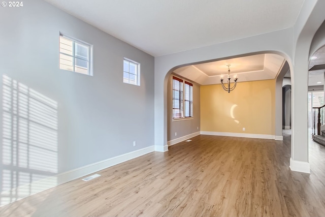 empty room featuring hardwood / wood-style floors, a wealth of natural light, and an inviting chandelier