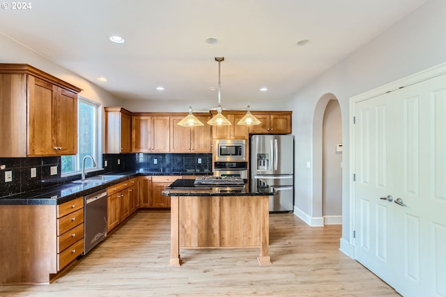 kitchen featuring light hardwood / wood-style floors, a kitchen island, appliances with stainless steel finishes, and decorative light fixtures