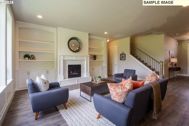 living room featuring built in shelves, dark hardwood / wood-style flooring, and a textured ceiling