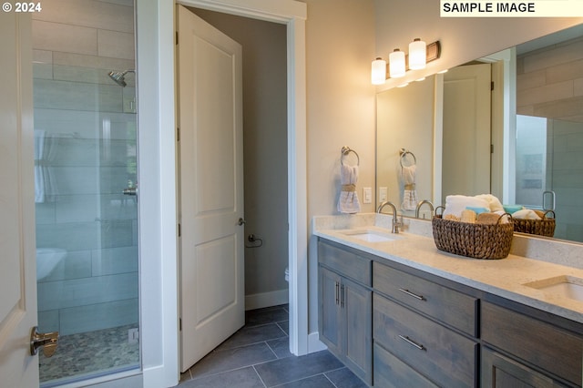 bathroom featuring tile patterned flooring, vanity, toilet, and walk in shower