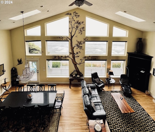 interior space with a textured ceiling, a skylight, light hardwood / wood-style flooring, and ceiling fan