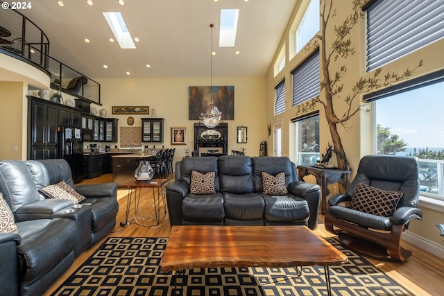 living room featuring hardwood / wood-style flooring, high vaulted ceiling, and a skylight