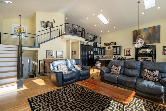 living room featuring hardwood / wood-style floors, an inviting chandelier, a skylight, and high vaulted ceiling