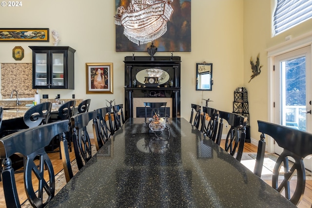 dining room with bar area, light hardwood / wood-style floors, a wealth of natural light, and a chandelier