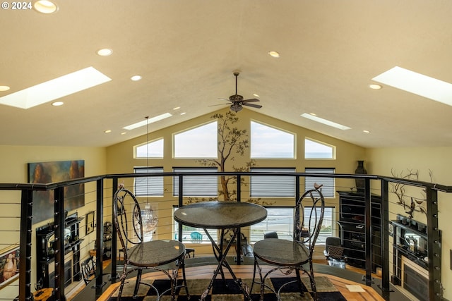 interior space featuring hardwood / wood-style flooring, lofted ceiling with skylight, and ceiling fan