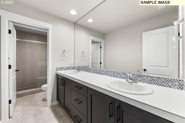 bathroom with vanity, toilet, a shower with door, and tasteful backsplash