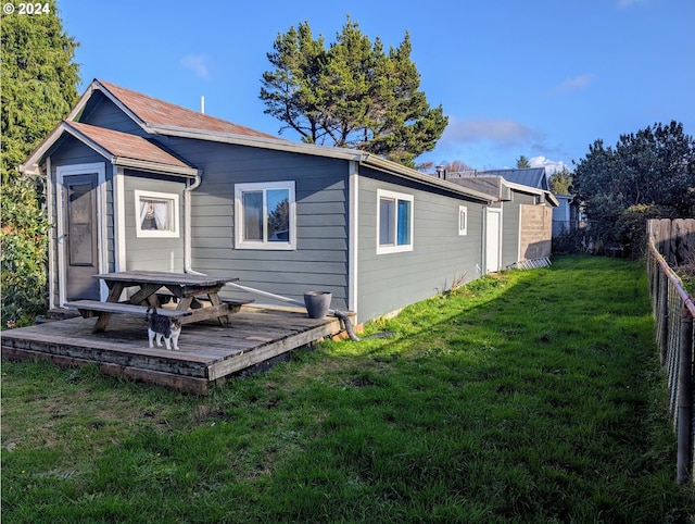 rear view of property featuring a wooden deck and a lawn