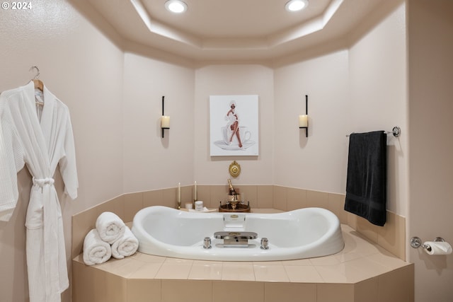 bathroom with a tray ceiling and tiled bath