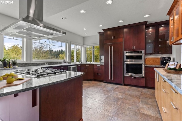 kitchen featuring dark stone counters, stainless steel appliances, island range hood, and a textured ceiling