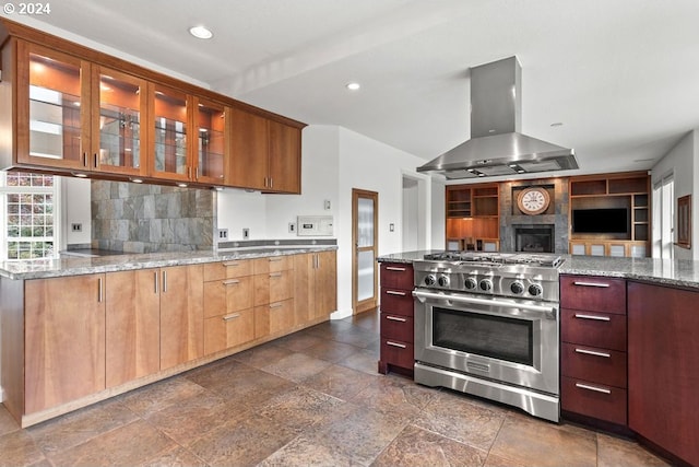 kitchen with island exhaust hood, light stone countertops, decorative backsplash, and high end stainless steel range oven