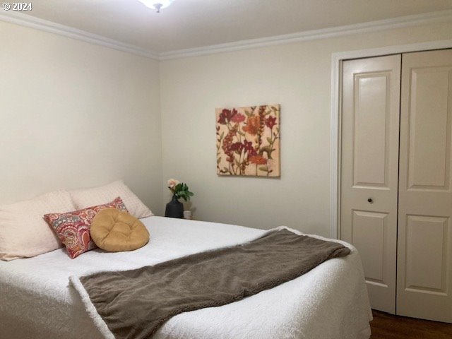 bedroom featuring wood-type flooring, ornamental molding, and a closet