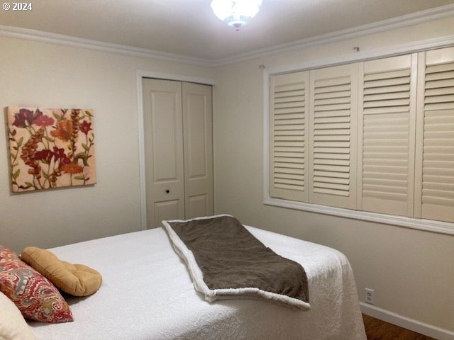 bedroom with dark hardwood / wood-style flooring, crown molding, and a closet