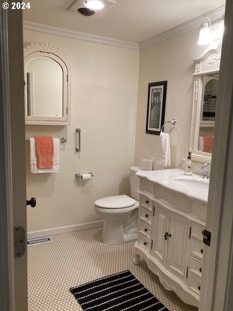 bathroom with vanity, toilet, and ornamental molding