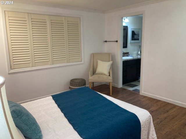 bedroom with connected bathroom, crown molding, and hardwood / wood-style floors