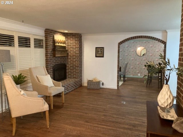 living area with a fireplace, dark hardwood / wood-style floors, and crown molding