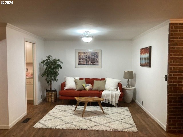 living room with crown molding and dark wood-type flooring