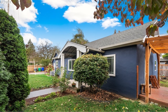 view of side of home featuring a deck, a yard, and central AC