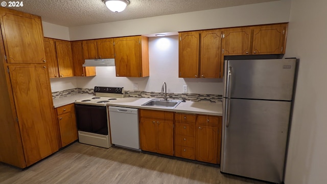 kitchen with sink, white appliances, light hardwood / wood-style floors, and a textured ceiling