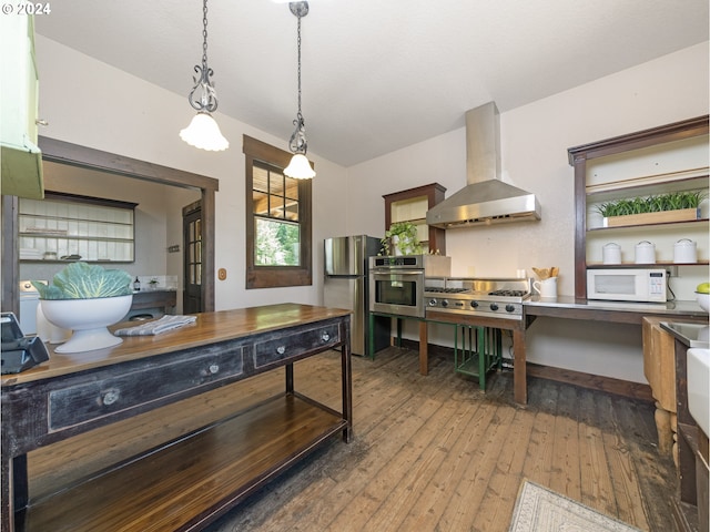 kitchen featuring hardwood / wood-style floors, stainless steel appliances, wall chimney exhaust hood, and hanging light fixtures