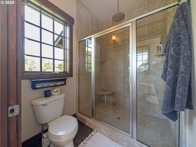 bathroom featuring a shower with door and toilet