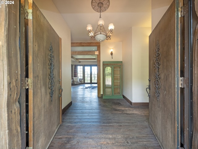 hall with beam ceiling, dark wood-type flooring, and an inviting chandelier