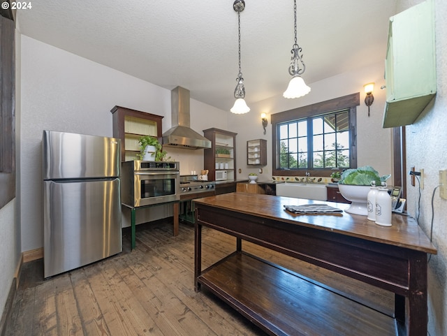 kitchen featuring hardwood / wood-style flooring, stainless steel appliances, wall chimney exhaust hood, and sink