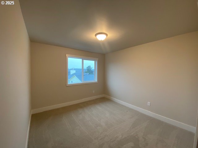 carpeted empty room featuring baseboards