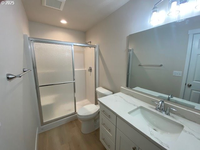 bathroom with toilet, a stall shower, wood finished floors, and vanity