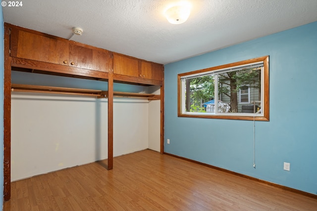 unfurnished bedroom featuring a textured ceiling, light hardwood / wood-style flooring, and a closet