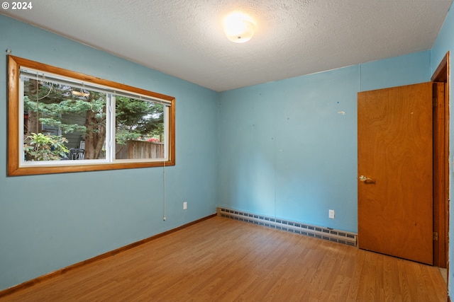 spare room featuring a baseboard radiator, a textured ceiling, and light hardwood / wood-style floors