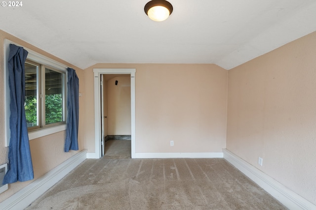 carpeted spare room with vaulted ceiling