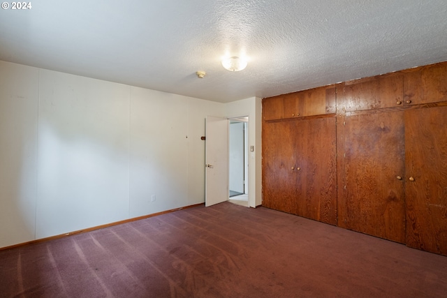 unfurnished bedroom with a closet, dark carpet, and a textured ceiling