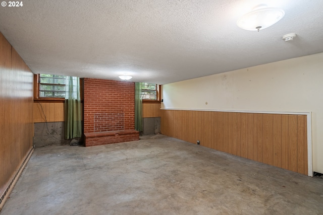 basement with wood walls, a textured ceiling, and a baseboard radiator