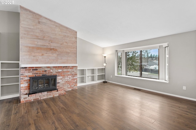 unfurnished living room with lofted ceiling, dark hardwood / wood-style floors, a fireplace, and built in shelves