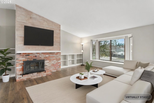 living room featuring dark wood-type flooring, lofted ceiling, and a brick fireplace