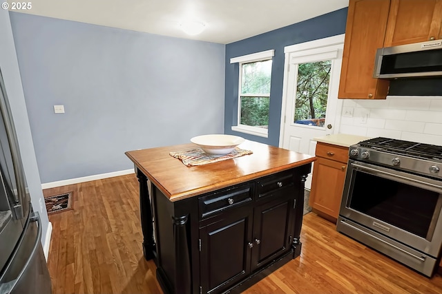 kitchen featuring backsplash, wood counters, light wood-type flooring, and stainless steel appliances