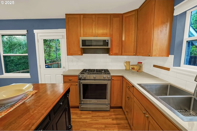 kitchen featuring wood counters, appliances with stainless steel finishes, backsplash, sink, and light hardwood / wood-style flooring