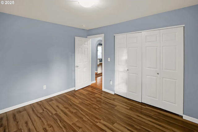 unfurnished bedroom with dark hardwood / wood-style floors and a closet