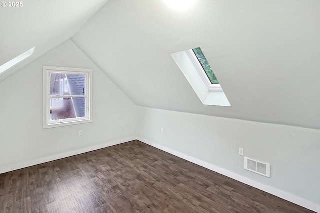 additional living space with lofted ceiling with skylight and dark wood-type flooring