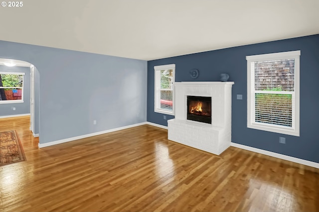 unfurnished living room with hardwood / wood-style floors and a brick fireplace