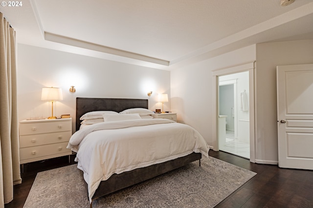 bedroom featuring ensuite bath and dark wood-type flooring