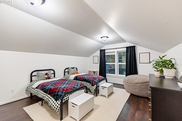 bedroom with hardwood / wood-style flooring, a textured ceiling, and vaulted ceiling