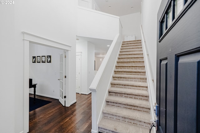 stairway featuring a high ceiling and wood-type flooring