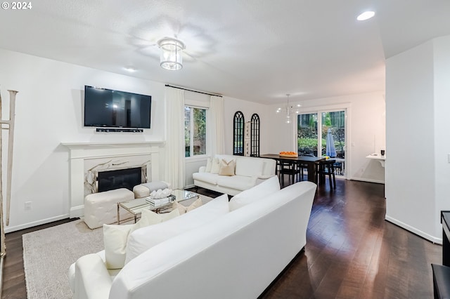 living room featuring dark hardwood / wood-style flooring, a high end fireplace, and an inviting chandelier