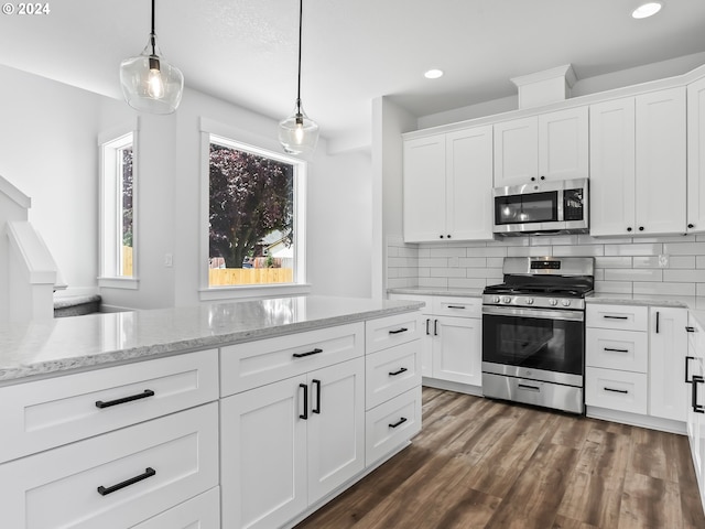 kitchen featuring stainless steel appliances, white cabinetry, and hanging light fixtures