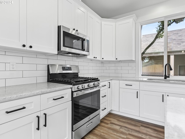 kitchen featuring sink, light stone countertops, dark hardwood / wood-style flooring, white cabinetry, and stainless steel appliances