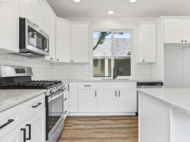 kitchen with white cabinets, light hardwood / wood-style floors, sink, and stainless steel appliances